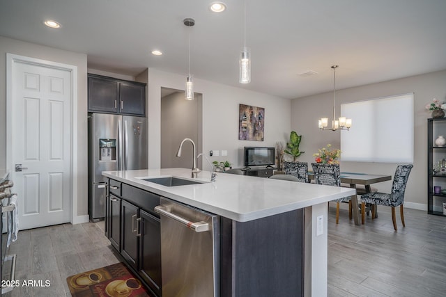 kitchen with a notable chandelier, a sink, light countertops, stainless steel appliances, and decorative light fixtures