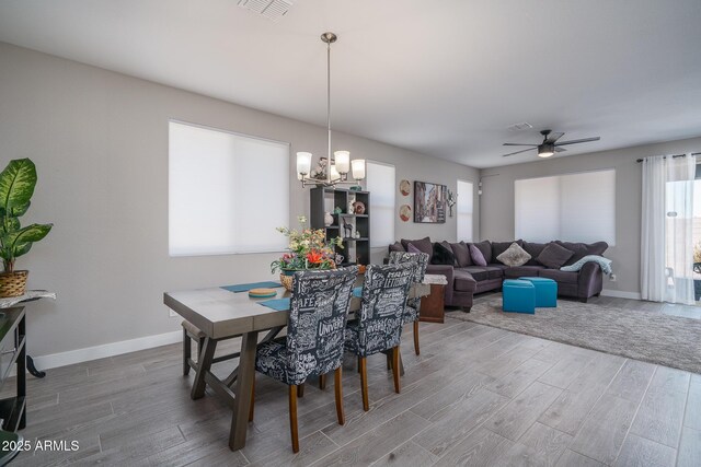 dining room featuring visible vents, baseboards, ceiling fan with notable chandelier, and wood finished floors