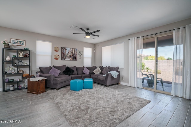 living room with wood tiled floor, baseboards, a ceiling fan, and visible vents