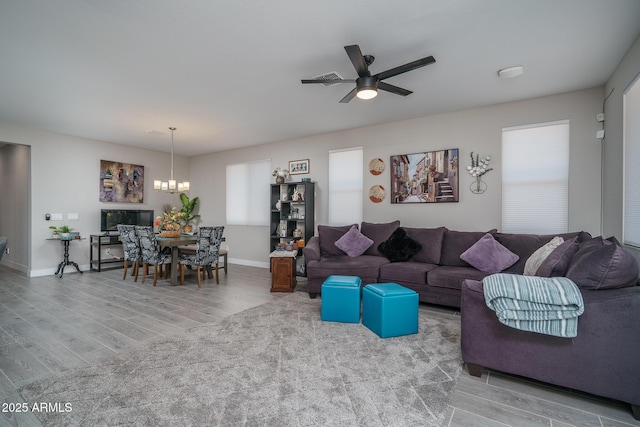 living room with baseboards, wood finished floors, and ceiling fan with notable chandelier