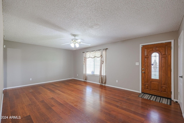 entrance foyer with ceiling fan, a textured ceiling, and dark wood-type flooring