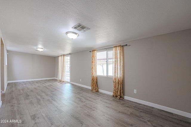 unfurnished room featuring light wood-type flooring and a textured ceiling