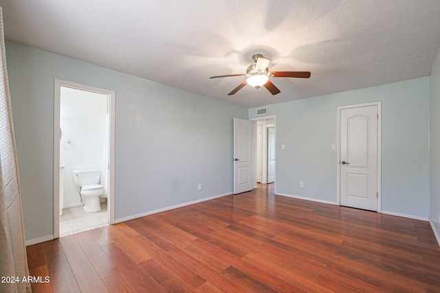 unfurnished bedroom featuring connected bathroom, dark hardwood / wood-style flooring, and ceiling fan