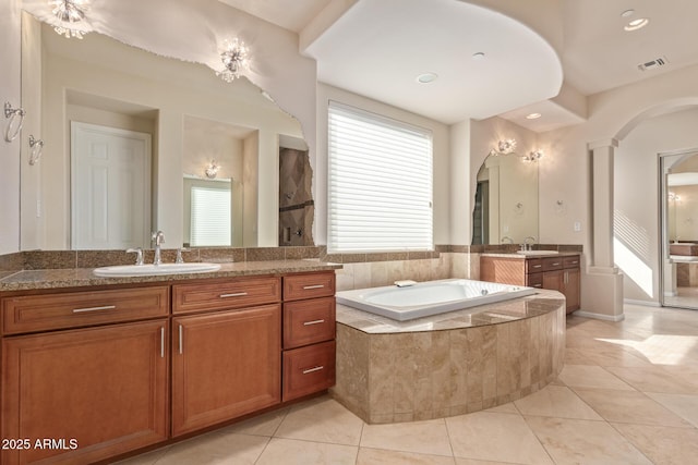 bathroom with tile patterned flooring, vanity, and tiled tub