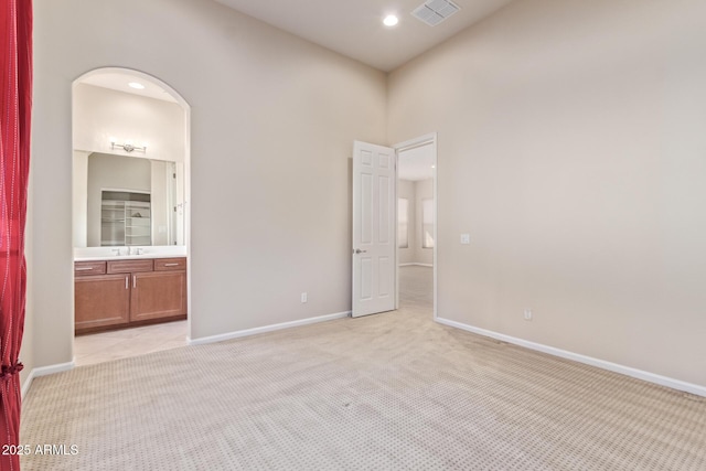 spare room with sink, light colored carpet, and a high ceiling