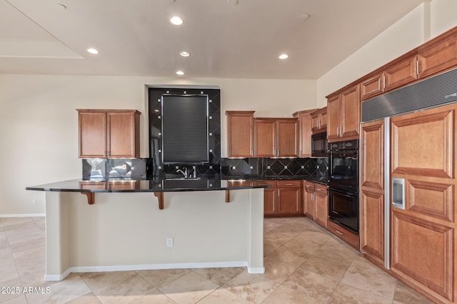 kitchen with a breakfast bar, tasteful backsplash, a kitchen island with sink, light tile patterned floors, and black appliances