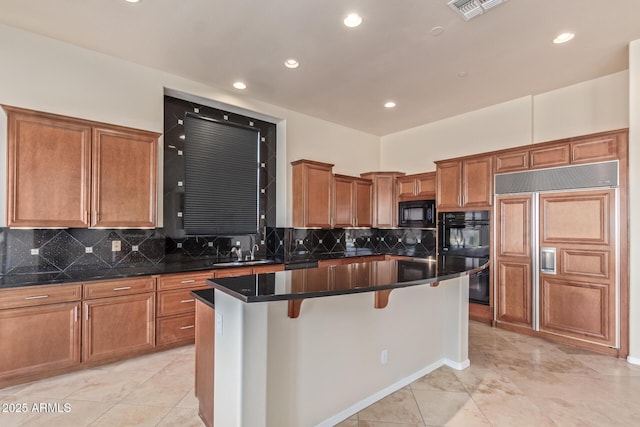 kitchen with a breakfast bar, sink, a center island with sink, decorative backsplash, and black appliances