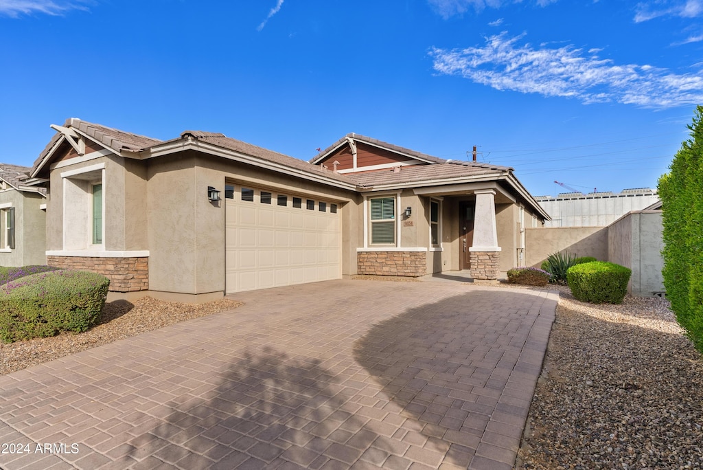 view of front facade with decorative driveway, stone siding, and stucco siding