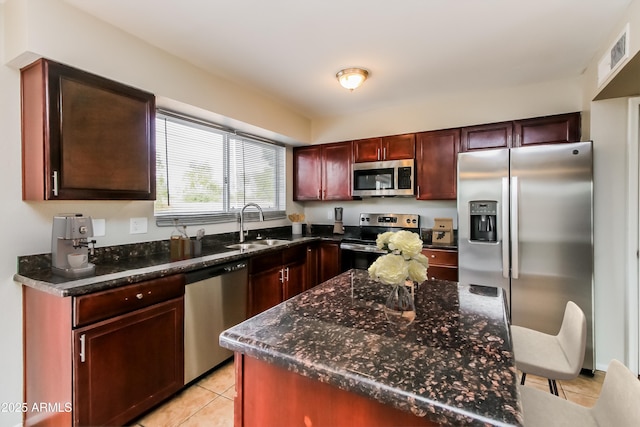 2922 S Cottonwood Dr, Tempe, AZ 85282 - kitchen featuring stainless steel appliances, a sink, light tile patterned floors, dark brown cabinets, and dark stone countertops