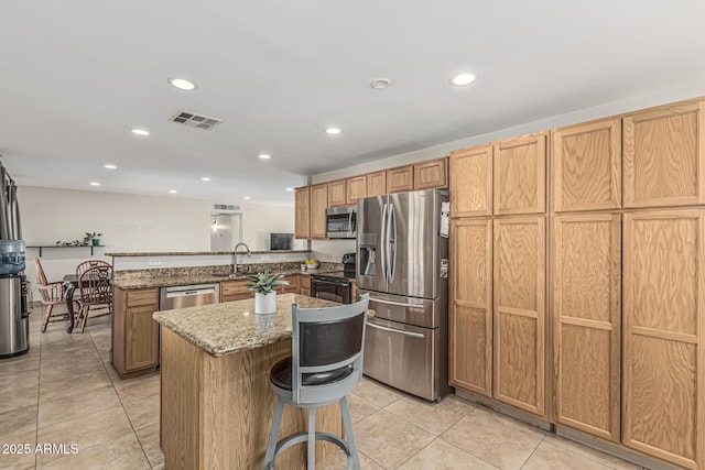 591 N Cheri Lynn Dr, Chandler, AZ 85225 - kitchen with appliances with stainless steel finishes, a peninsula, light tile patterned floors, a kitchen island, and light stone counters