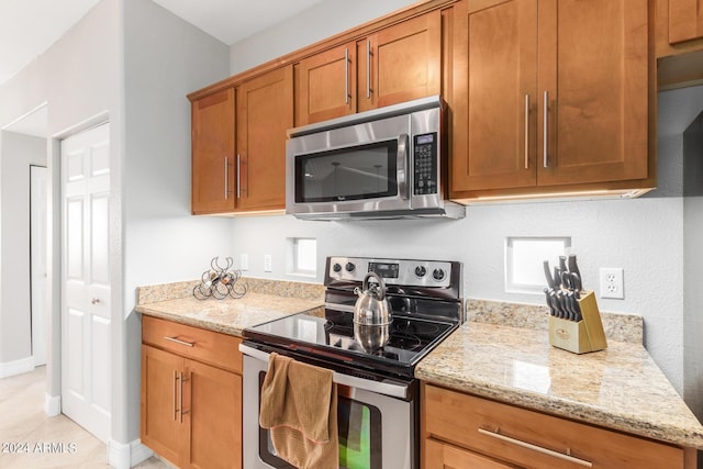 kitchen featuring light stone countertops, appliances with stainless steel finishes, and light tile patterned floors