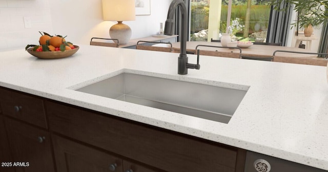 interior details with sink, dark brown cabinets, and light stone counters