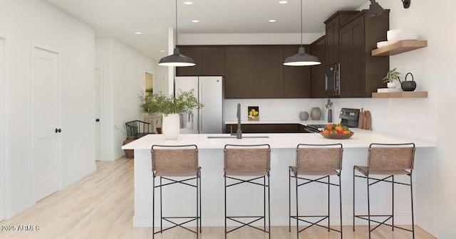 kitchen with white refrigerator, sink, kitchen peninsula, electric range, and a breakfast bar area