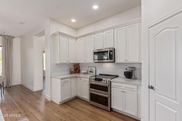 kitchen featuring stainless steel appliances, light countertops, decorative backsplash, light wood-style flooring, and recessed lighting