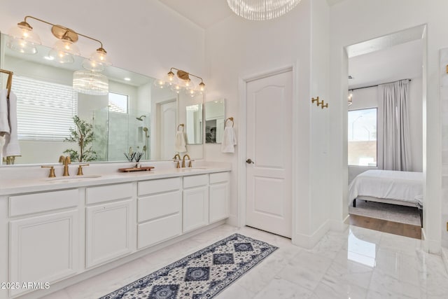 ensuite bathroom with plenty of natural light, a shower stall, marble finish floors, and double vanity