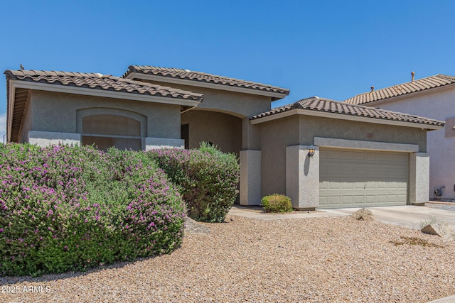 mediterranean / spanish house featuring a garage, stucco siding, and driveway