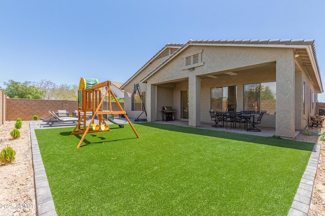rear view of property featuring a playground, stucco siding, and a patio area