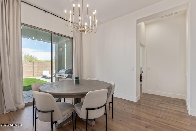 dining area featuring a chandelier, wood finished floors, and baseboards