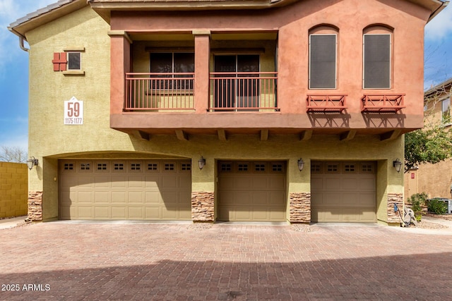 view of front of house with stucco siding, an attached garage, and a balcony