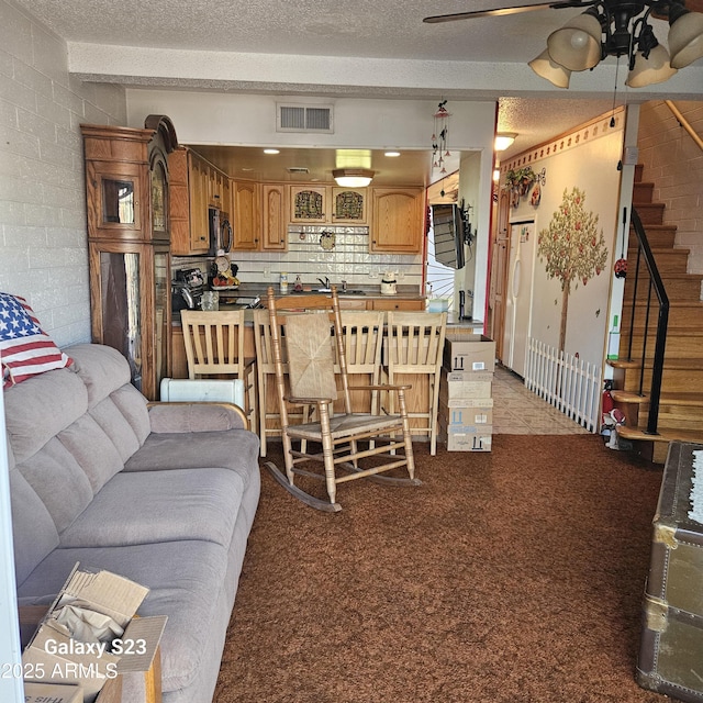 living room featuring beamed ceiling, light colored carpet, a textured ceiling, and ceiling fan