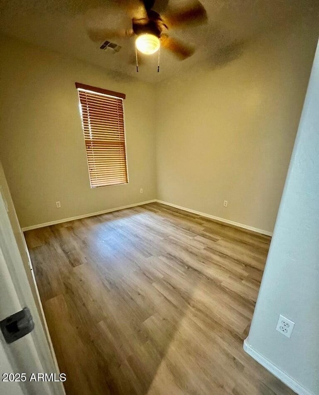 empty room featuring visible vents, ceiling fan, baseboards, and wood finished floors