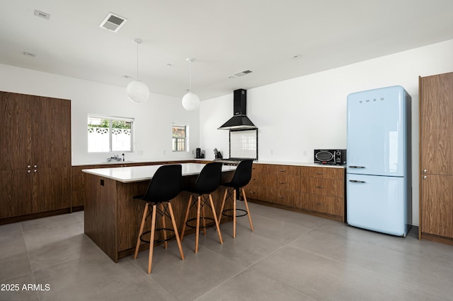 7646 E Catalina Dr, Scottsdale, AZ 85251 - kitchen with visible vents, freestanding refrigerator, a breakfast bar area, a center island, and exhaust hood