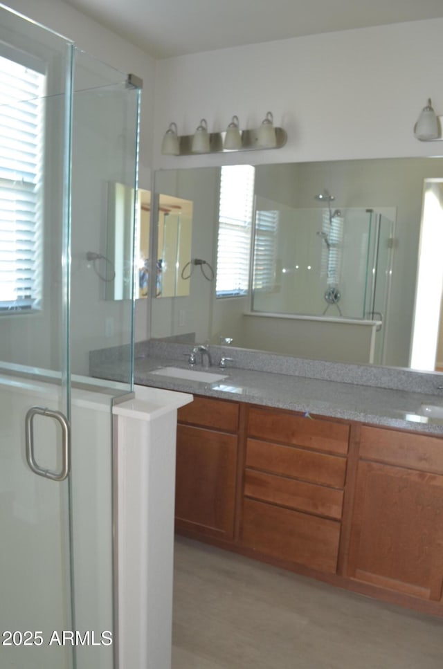 full bath featuring double vanity, plenty of natural light, a shower stall, and a sink