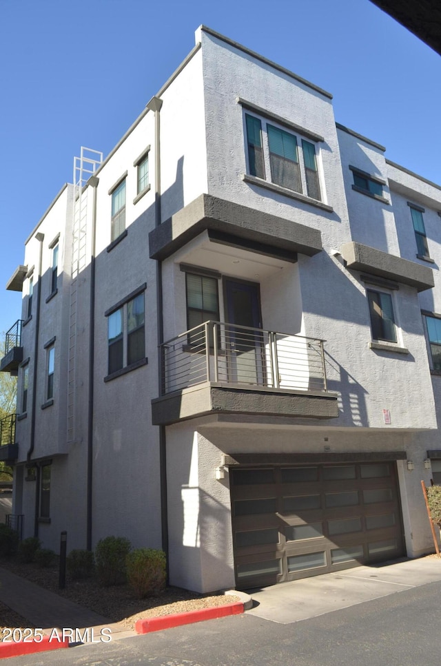 view of front of property with a garage, a balcony, and stucco siding