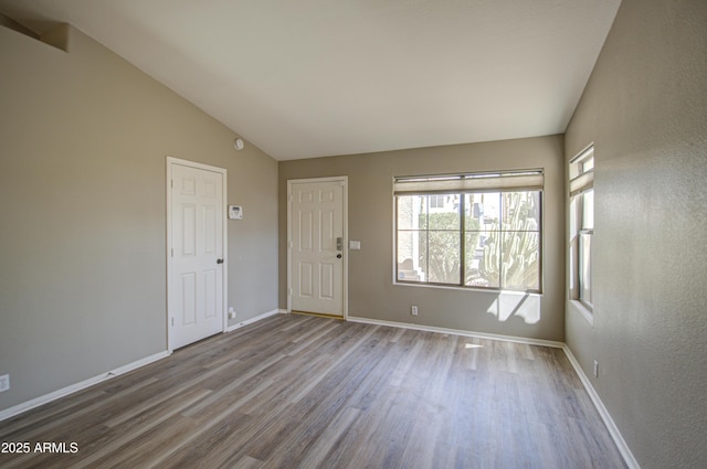 interior space with wood finished floors, baseboards, and vaulted ceiling