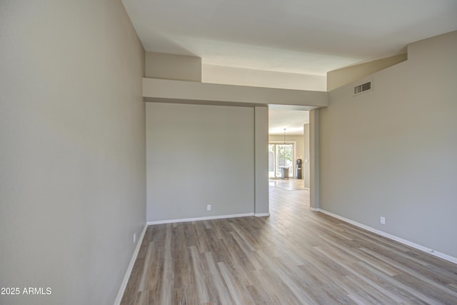 empty room featuring visible vents, baseboards, and wood finished floors