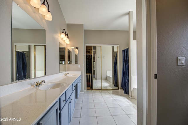 bathroom featuring a sink, a walk in closet, double vanity, and tile patterned floors