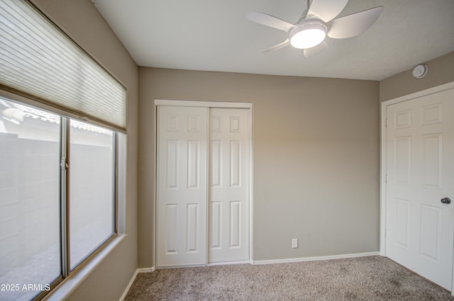 unfurnished bedroom with a closet, carpet floors, baseboards, and ceiling fan