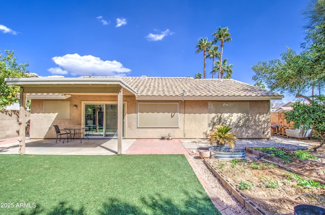 back of house featuring fence, a tiled roof, stucco siding, a lawn, and a vegetable garden