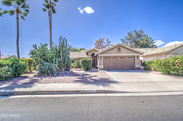 view of front of house featuring a tiled roof, stucco siding, driveway, and an attached garage