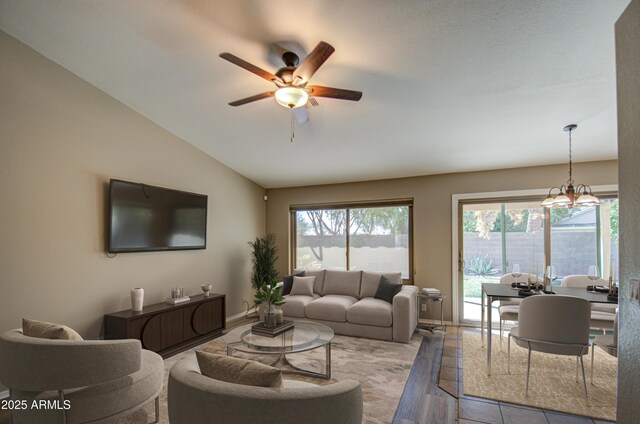 living area featuring vaulted ceiling, baseboards, and ceiling fan