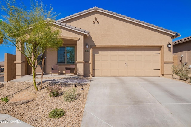 view of front of property featuring concrete driveway, a tile roof, an attached garage, and stucco siding