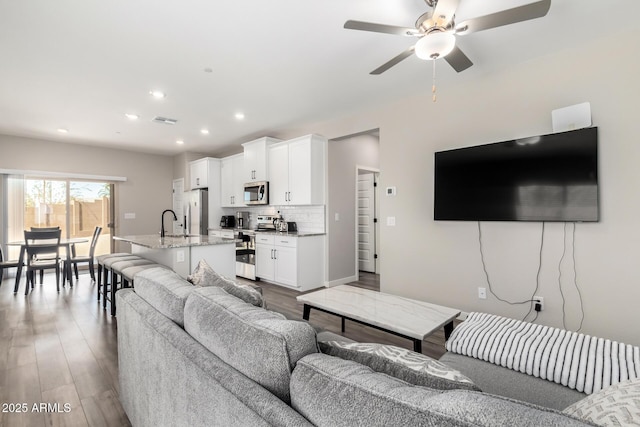 living room featuring dark wood-style floors, a ceiling fan, visible vents, and recessed lighting