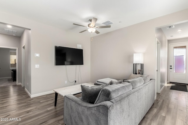 living area featuring visible vents, baseboards, and wood finished floors