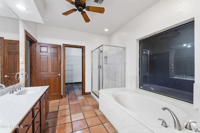 bathroom with ceiling fan, vanity, a bath, a stall shower, and a walk in closet