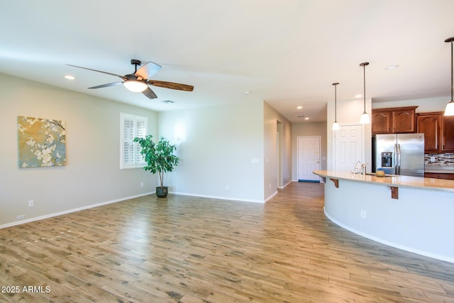 42531 W Heavenly Pl, Maricopa, AZ 85138 - kitchen featuring open floor plan, light wood finished floors, a kitchen bar, and stainless steel fridge with ice dispenser