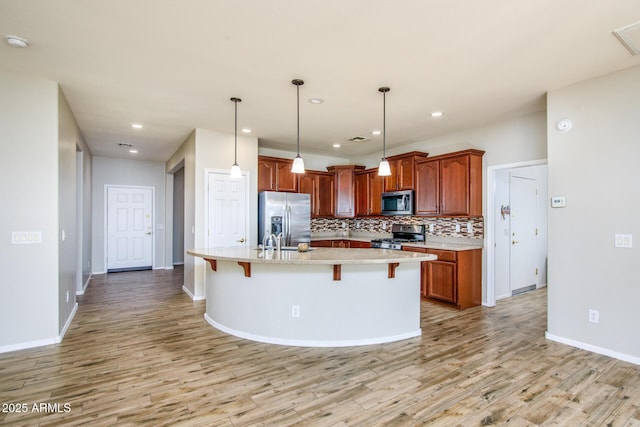 42531 W Heavenly Pl, Maricopa, AZ 85138 - kitchen with light wood finished floors, appliances with stainless steel finishes, a breakfast bar, and backsplash