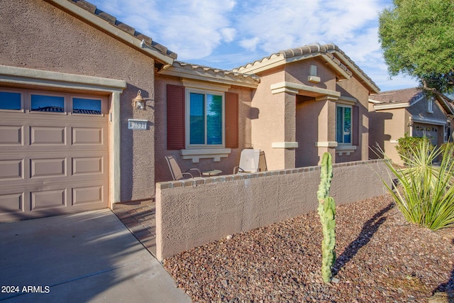 view of front of home with a garage, a tile roof, fence, and stucco siding