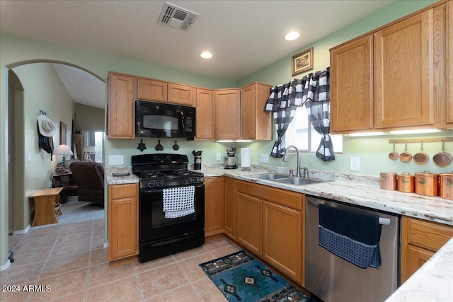 kitchen with black appliances, light tile patterned floors, sink, and light stone countertops