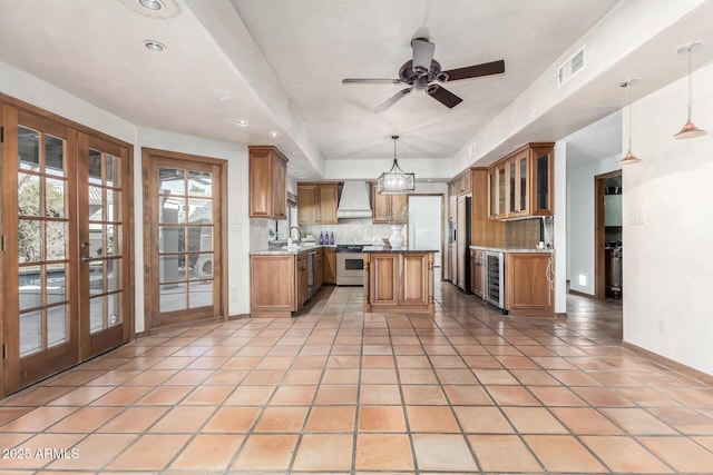 kitchen with a center island, wall chimney exhaust hood, beverage cooler, and decorative light fixtures