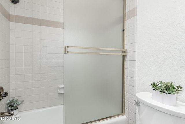 bathroom with shower / bath combination with glass door and toilet