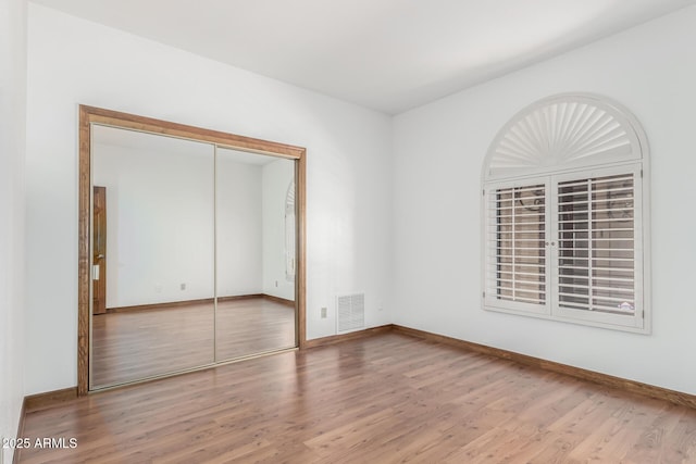 unfurnished bedroom with hardwood / wood-style floors and a closet