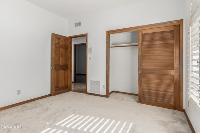 unfurnished bedroom with light colored carpet and a closet