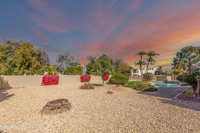 yard at dusk with a fenced in pool