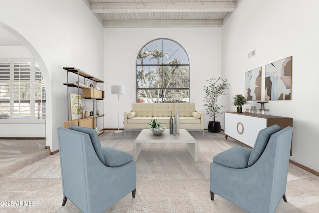 carpeted living room with beam ceiling and a high ceiling