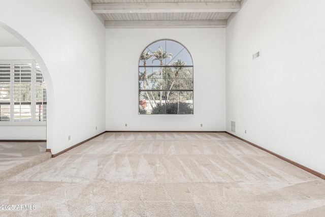 carpeted empty room featuring beam ceiling